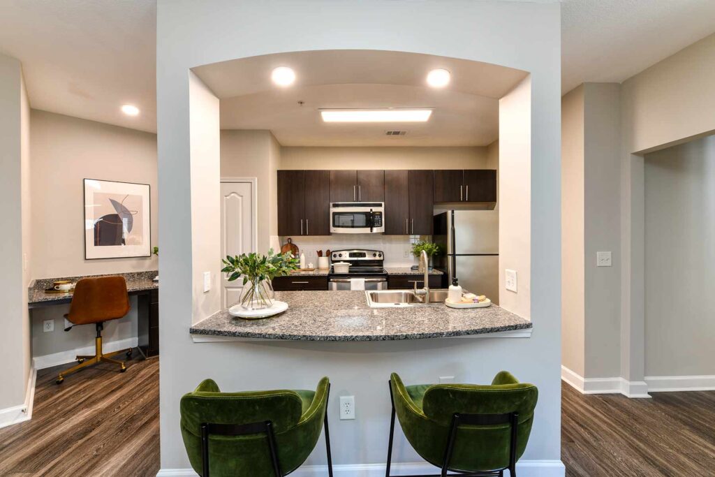 Breakfast bar seating looking into Kitchen with granite countertops, stainless steel appliances, and tile backsplash