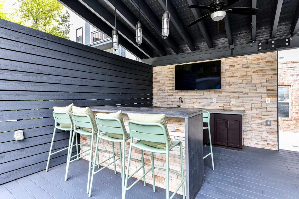 Covered outdoor kitchen with bar seating and TV